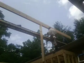 Carpenter setting a ridge beam over a new addition frame — Ice Dam Removal by Roofing Brothers in Bettendorf