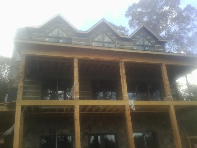 Dormers and porch framing on a large log home under construction — Roof Coating work by our crew in Bettendorf