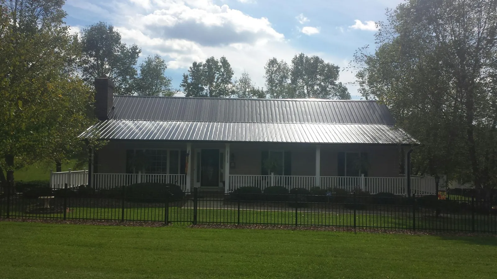 Gray metal roof on a brick ranch with a full width front porch — Gutter Guard Installation work by our crew in Bettendorf