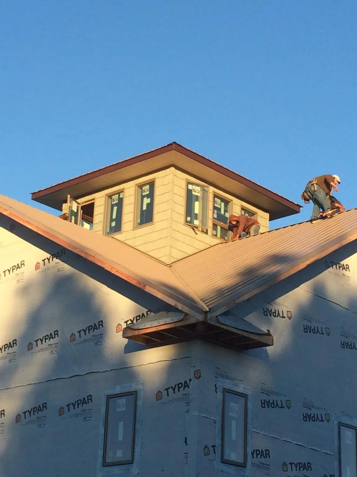 Roofers working around a rooftop cupola on a new metal roof at sunset — Roof Waterproofing in Bettendorf by Roofing Brothers